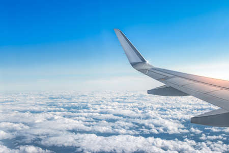 Airplane wing above the clouds. View from airplane window. Air travel and transportation concept.の写真素材