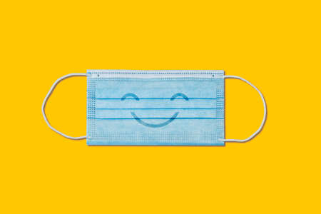 Happy smiling medical face mask on yellow background.の写真素材