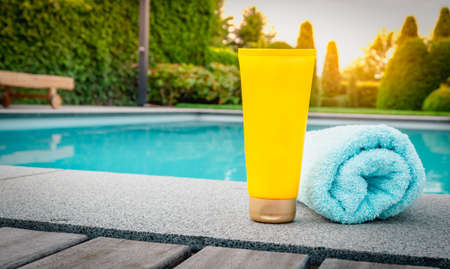 Skin care and protection against harmful sun rays. Yellow tube of sunscreen at the swimming pool.の写真素材
