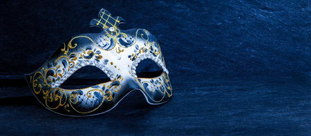 Festive carnival mask with gold glitter decorations and diamond beads on dark blue background.の写真素材