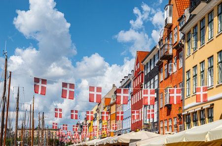 Waving danish flags above touristic street with colorful buildings in Nyhavn, Copenhagen in Denmark.の写真素材