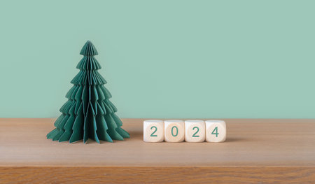 Wooden cubes with year number 2024 and paper Christmas tree on green background.の写真素材