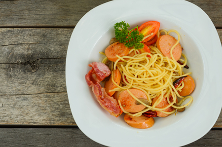 Pasta spaghetti with fried sausage in white plate on wood table background.overhead view.の写真素材