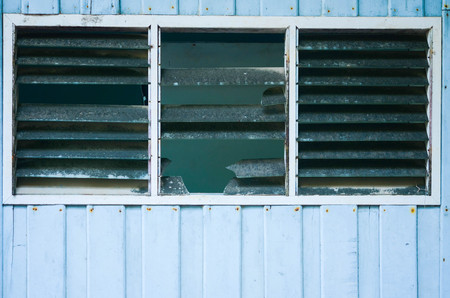 Old vintage barn with and broken window on the blue wall.の写真素材