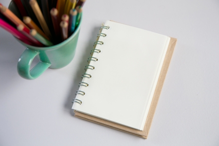 notebook with color pencils in a green mug