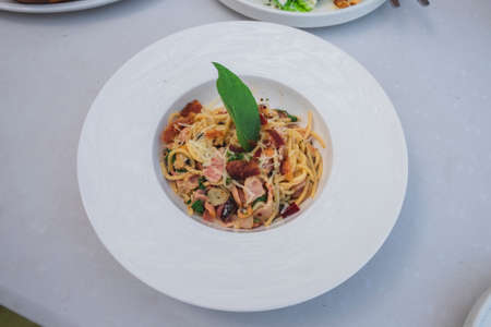 Top view of Stir-fried Spicy Spaghetti Seafood or "Spaghetti Pad Kee Mao", Italian fusion food in Thai Style serve with white dish on the wooden desk.の写真素材
