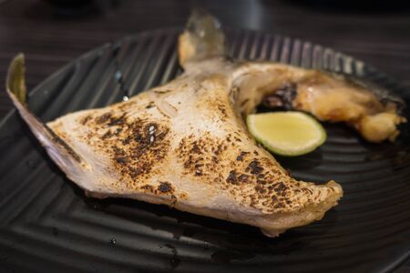 Salt grilled fish cheek on balck ceramic plateの写真素材