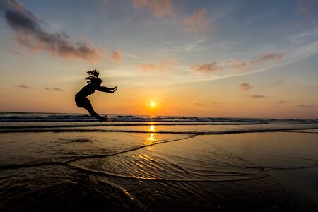 Happy Woman Jumping in Sea Sunsetの写真素材