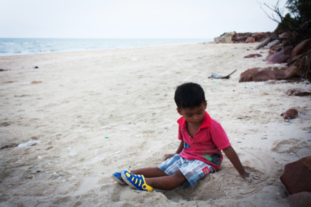 vintage photo boy sitting playing n the beach looking to seaの写真素材