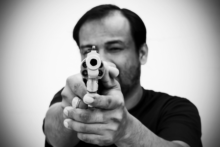 black and white of man holding gun and pointing his gun revolver. Selectively concentrated on the front of the gun.の写真素材