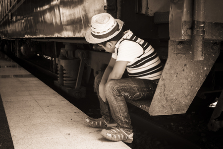 abstract of asian little boy sitting alone at the train station vintateの写真素材