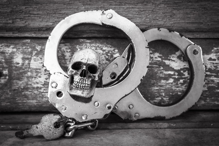 still life and vintage of skull human with handcuff on old wooden  backgroundの写真素材