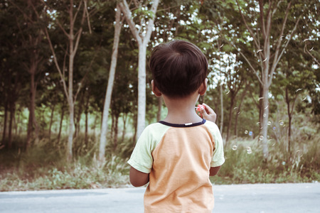 Little asian boy playing with bubble wand blowing soap bubbles,vintage toneの写真素材