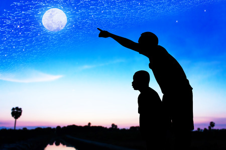 Silhouette of father use hand point his son look at meteor shower and star on the skyの写真素材