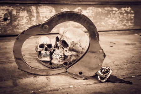 still life and vintage of skull human with handcuff on old wooden  backgroundの写真素材