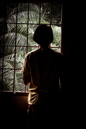 asian girl sad looking out the window in your home