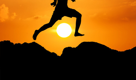 silhouette of theyoung man jumpping at mountain yellow sunset backgroundの写真素材