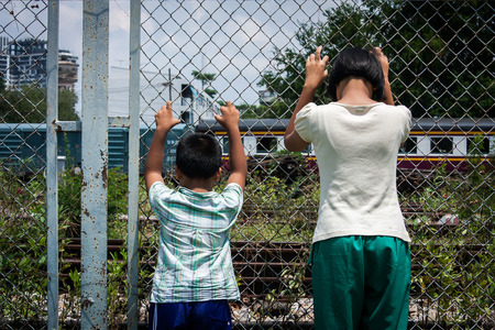 asian girl and boy sad  hand hold jail at Railroad,railway stationの写真素材