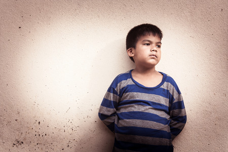 asian boy sad alone standing near old wall cement,vintage toneの写真素材