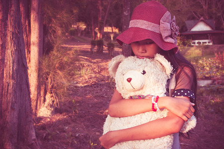 asian cute girl standing alone at the lagoon and hand bear hug,vintage toneの写真素材