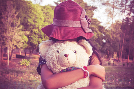 asian cute girl standing alone at the lagoon and hand bear hug,vintage toneの写真素材
