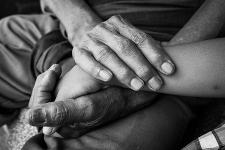 asian kids little boy hand touches and holds an old man wrinkled hands,black and white toneの写真素材