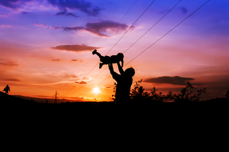 silhouettes of father and son play at mountain range and high voltage electricity pylon sunset backgroundの写真素材