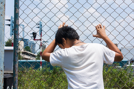 asian little girl sad hand hold jail at Railroad,railway stationの写真素材