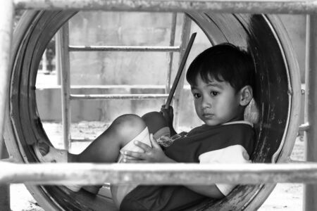 asian boy sitting alone at playground ,black and white toneの写真素材