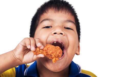 little boy eating fried chicken isolate backgroundの写真素材