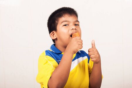 little boy eating fried chicken isolate backgroundの写真素材