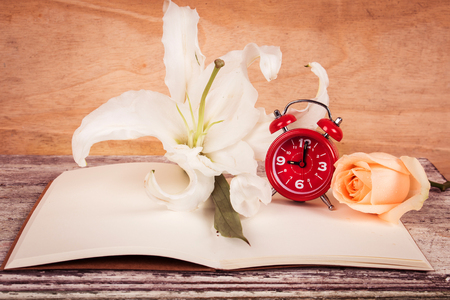 lilly flower and watch on note book wooden backgroundの写真素材