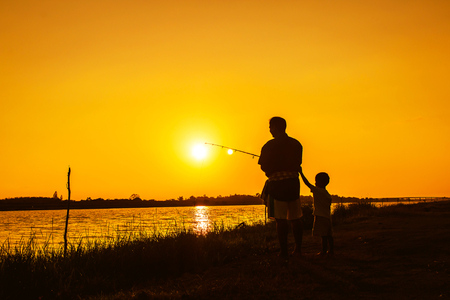 father and son fishing in the river sunset backgroundの写真素材