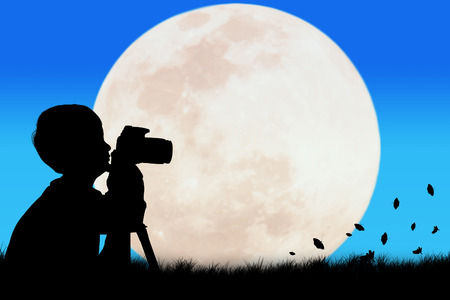 Silhouette of little boy taking camera full moon backgroundの写真素材
