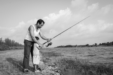 son and dad fishing at river ,black and white toneの写真素材