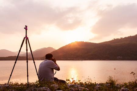 yound man taking camera at dam in the eveningの写真素材