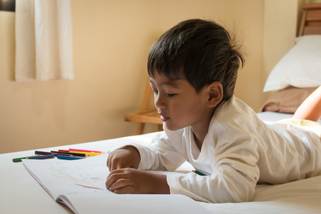 little asian boy paint on white book in the roomの写真素材
