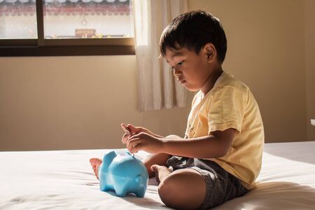 cute asian boy saving money in piggy bankの写真素材