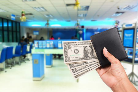 Hand women hold money in black wallet on the bank background