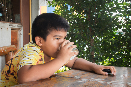 Cute little boy drinking water in the parkの写真素材
