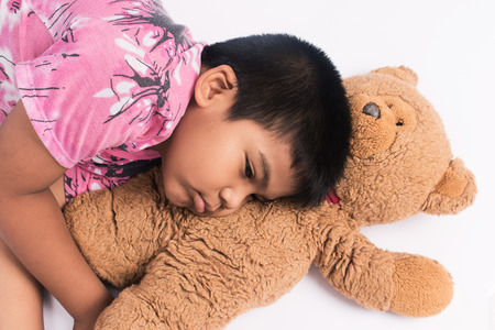 Cute little boy laying on floor with brown teddy bearの写真素材