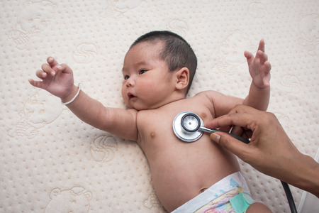 Hand doctor exams  baby with stethoscope,Pediatrician examines two months newborn asian girl,Doctor using a stethoscope to listen to child baby chest checking heartbeatの写真素材