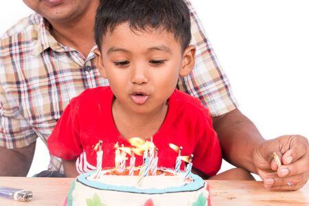 Cute little child boy with his father blowing birthday cakeの写真素材
