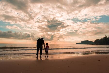 Happy family cute little boy ans dad play on beach sunrise backgroundの写真素材