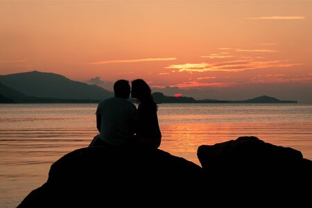 Romantic of couple love standing on the stone looking sunset at seaの写真素材