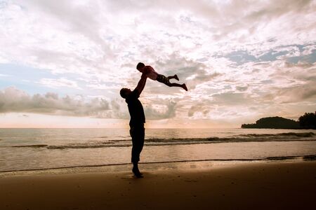 Happy family cute little boy ans dad play on beach sunrise backgroundの写真素材
