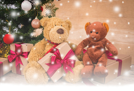 Teddy bear with brown gift box and chirstmas tree on wooden backgroundの写真素材