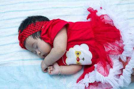 Santa suit baby is sleeping on the bedの写真素材
