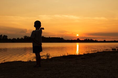 Cute little boy play at river sunset backgroundの写真素材