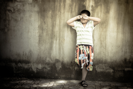 asian boy crying alone at old wall ,vintage toneの写真素材
